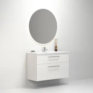 Tvålådig vit badrumsmöbel under rund spegel med bakgrundsbelysning, samt handfat och dekoration på bänkskivan.