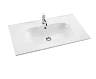 Vit rektangulär tvättställ med kran och avloppshål.