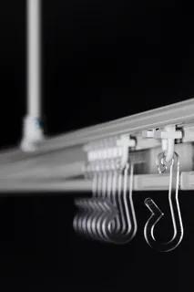 Takmonterad skena med flera genomskinliga krokar i plast på rad.