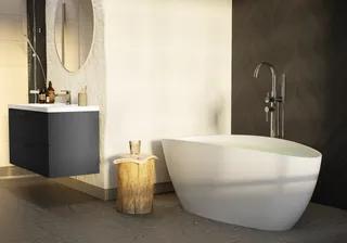 Modernt badrum med fristående badkar, rund spegel, svart flytande tvättställ, och träpall med dekor.