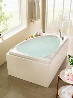 Rektangulärt badkar fyllt med vatten, placerat i ett ljust badrum intill stora fönster.