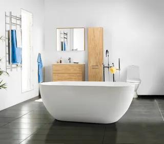 Modernt badrum med fristående badkar, toalett, spegel och träskåp. Handduk hänger på väggen.