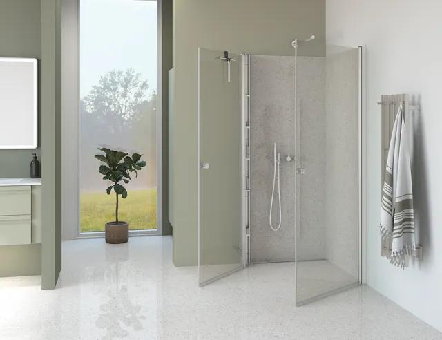 Duschhörn i glas, vinkel, vitt badrum med handduk och växt.