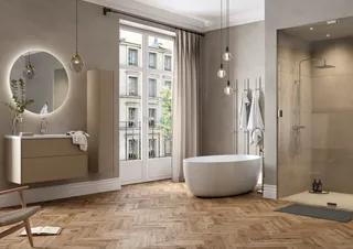 Modernt badrum med fristående badkar, rund spegel med belysning, duschkabin och trägolv. Hängande glödlampor ovanför.