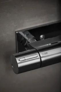 Silverfärgad dörrstängare på mörk yta med texten "IAR" synlig.