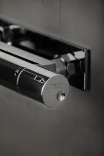 Kromfärgad termostatblandare monterad på en vägg, märkt "mora".