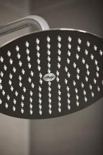 Rund regnduschhuvud med många små, vita munstycken och silverfärgad kant.